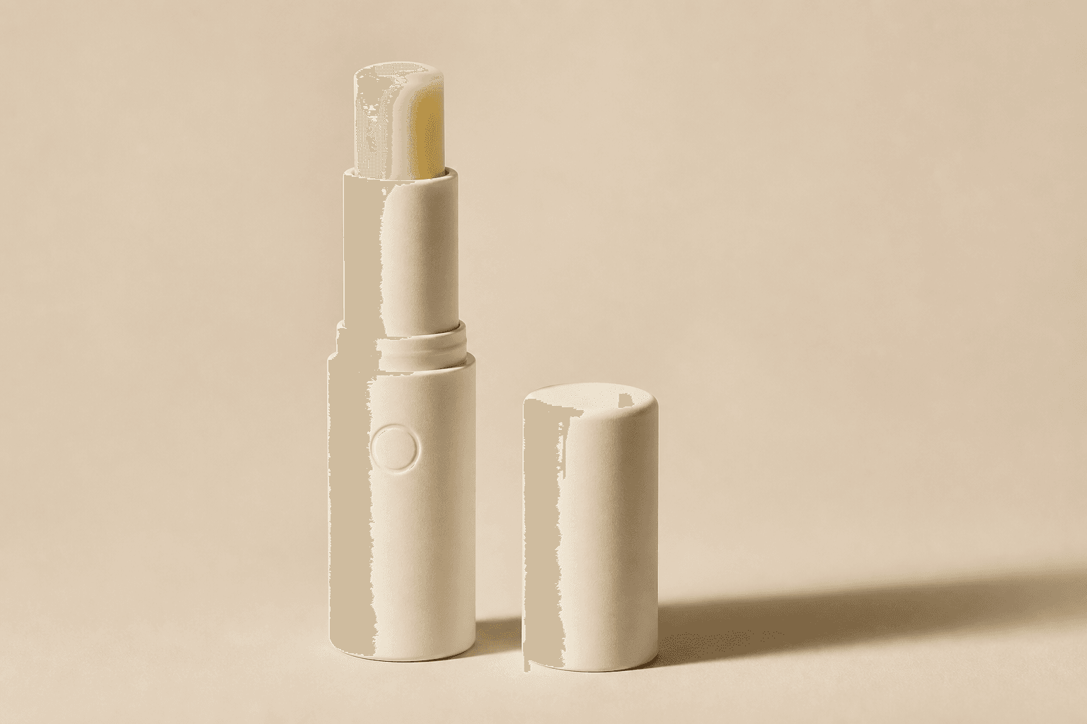 Unlabeled warm-ivory lip balm tube with its cap beside it