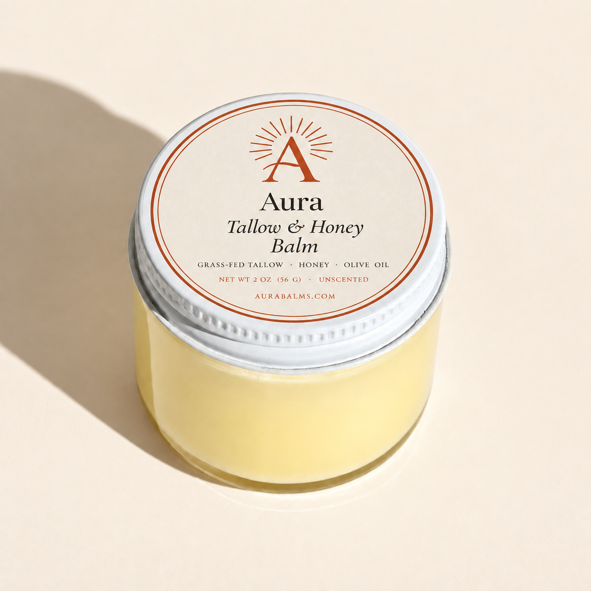 Clear glass balm jar with a white Aura-labelled lid on a warm cream background