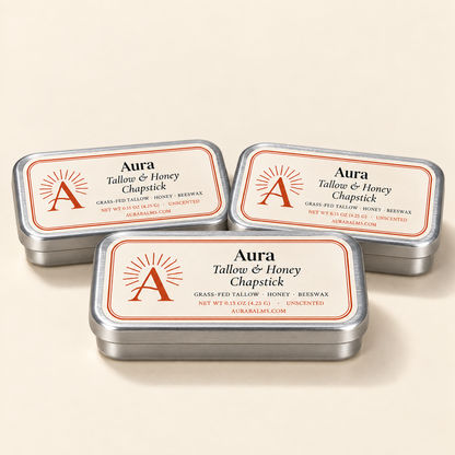 Three silver slider chapstick tins with cream Aura labels on a warm cream background